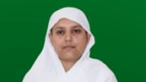 Portrait of a woman wearing a white hijab against a solid green background.