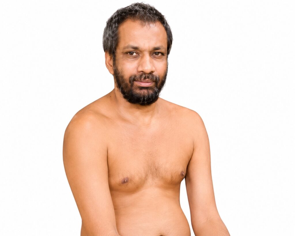 Man with short dark hair and a beard, shirtless, looking at the camera against a white studio background.