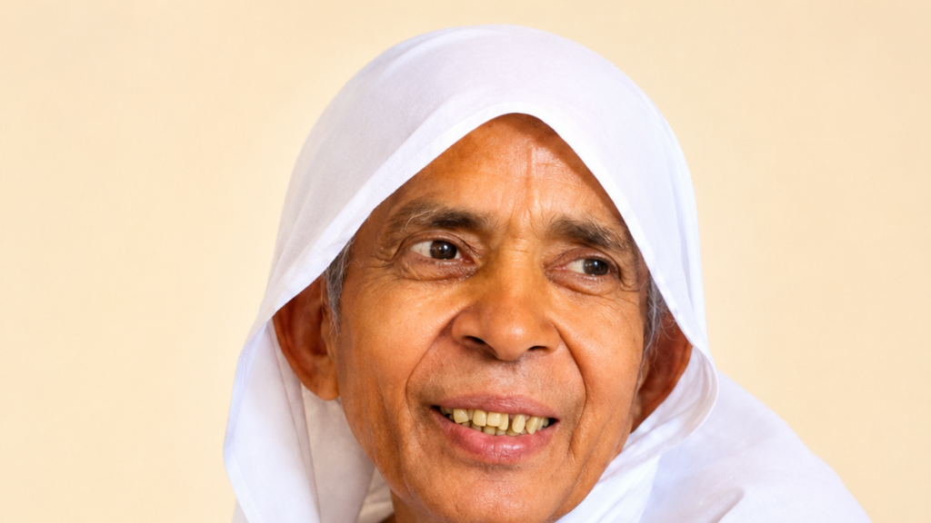 Close-up of an elderly woman in a white headscarf smiling softly against a beige background.