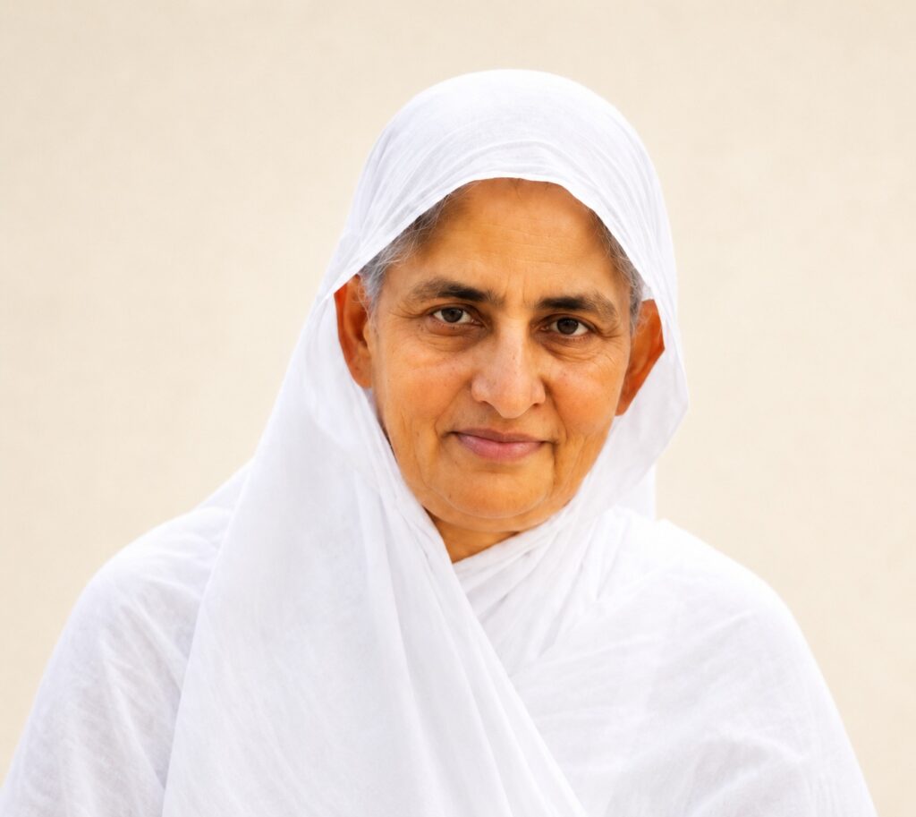 Older woman in a white headscarf and robe, smiling softly at the camera.