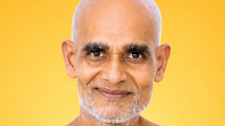 Close-up portrait of a smiling bald man with a gray beard against a bright yellow background.