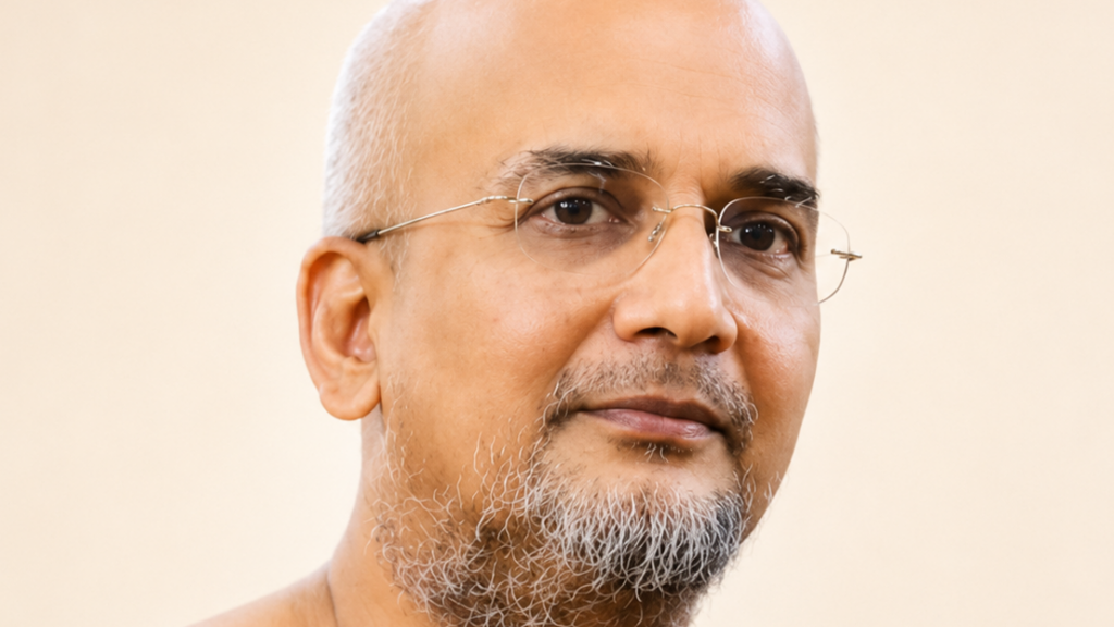 Close-up portrait of a balding man with rimless glasses and a gray beard looking at the camera.