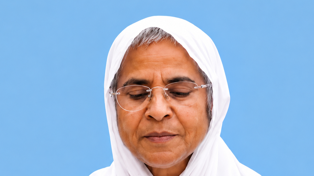 Portrait of a woman wearing a white hijab and glasses, looking downward against a blue background.
