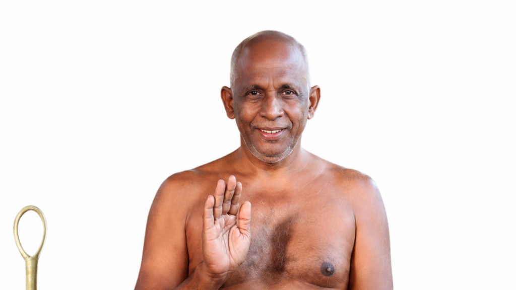 Older man with a cheerful expression raises his right hand in a greeting/blessing gesture, shirtless with a ceremonial staff visible on the left side.