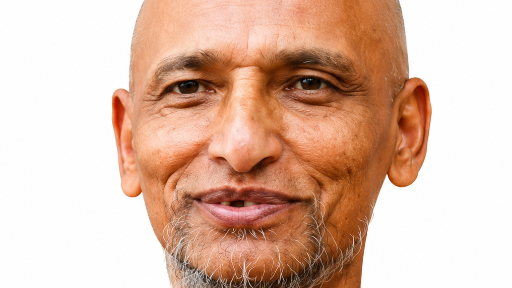 Close-up portrait of a smiling bald man with a gray goatee against a white background.
