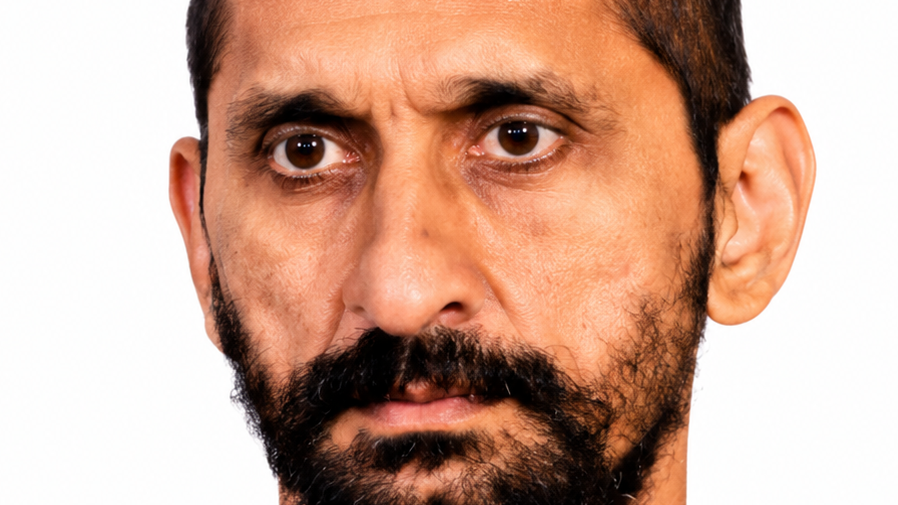 Close-up of a bearded man with a tense, wary expression and wide eyes.