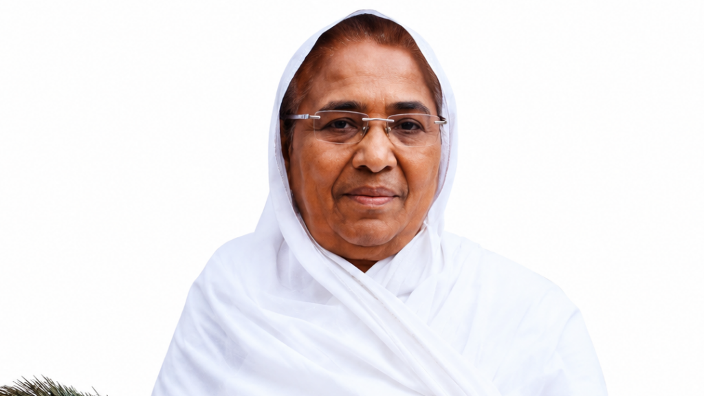 Elderly woman in a white hijab and glasses, facing the camera against a white background.