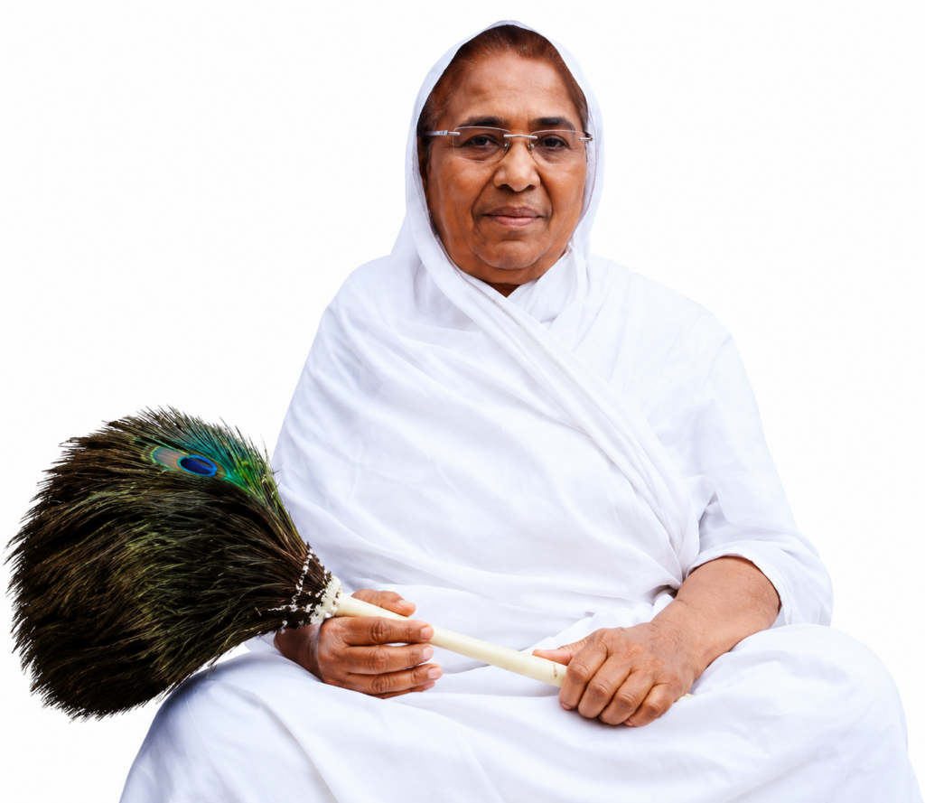 Older woman in white traditional clothing and headscarf sits holding a peacock feather broom in her lap while looking at the camera.