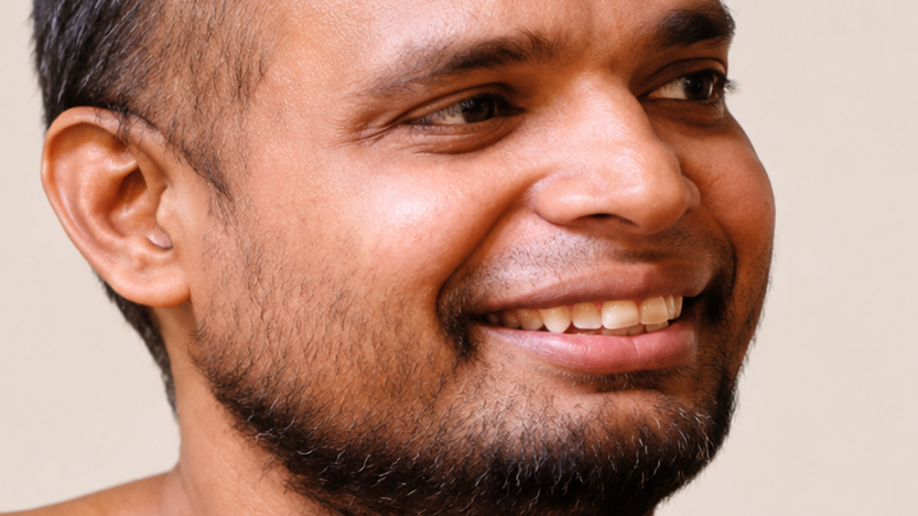 Close-up of a man smiling, showing teeth and a trimmed beard.