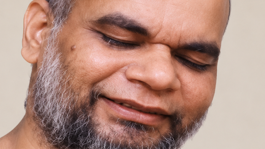 Close-up of a man with a salt-and-pepper beard smiling with his eyes closed.