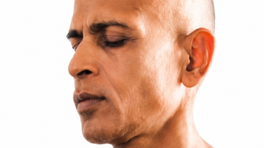 Close-up of a bald man with a serious, downward-looking expression.