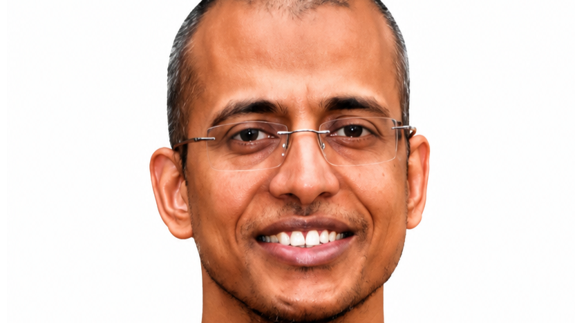 Smiling man wearing glasses, looking at the camera, with a light background