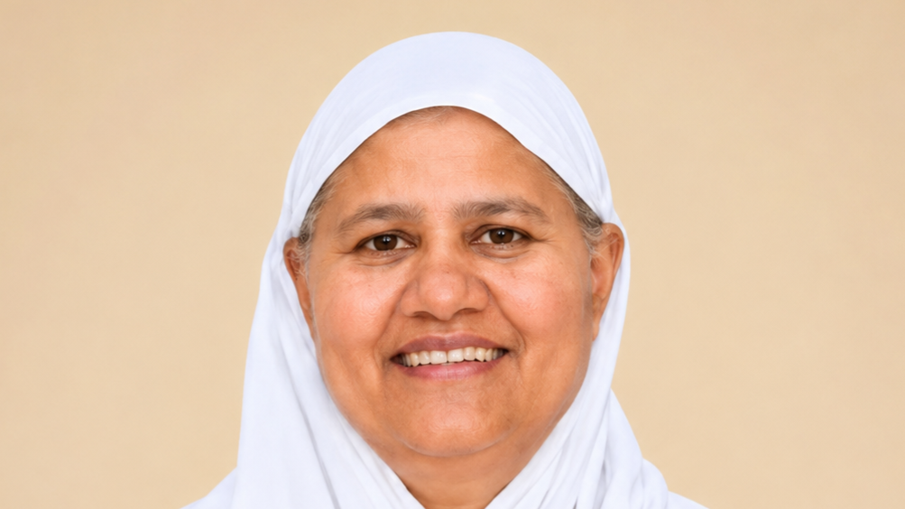 Smiling woman wearing a white hijab against a beige background (portrait)