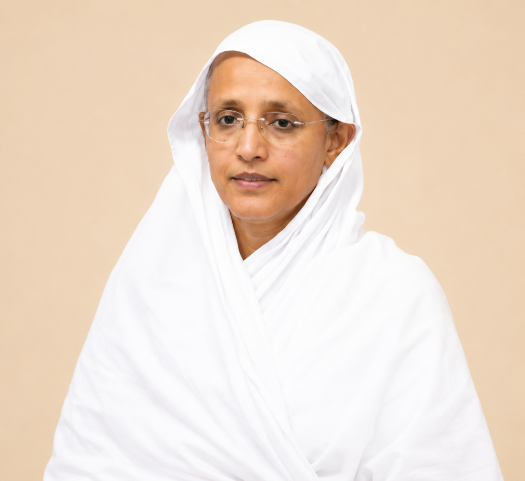 Portrait of a middle-aged woman wearing a white hijab and glasses against a beige background, looking softly at the camera.