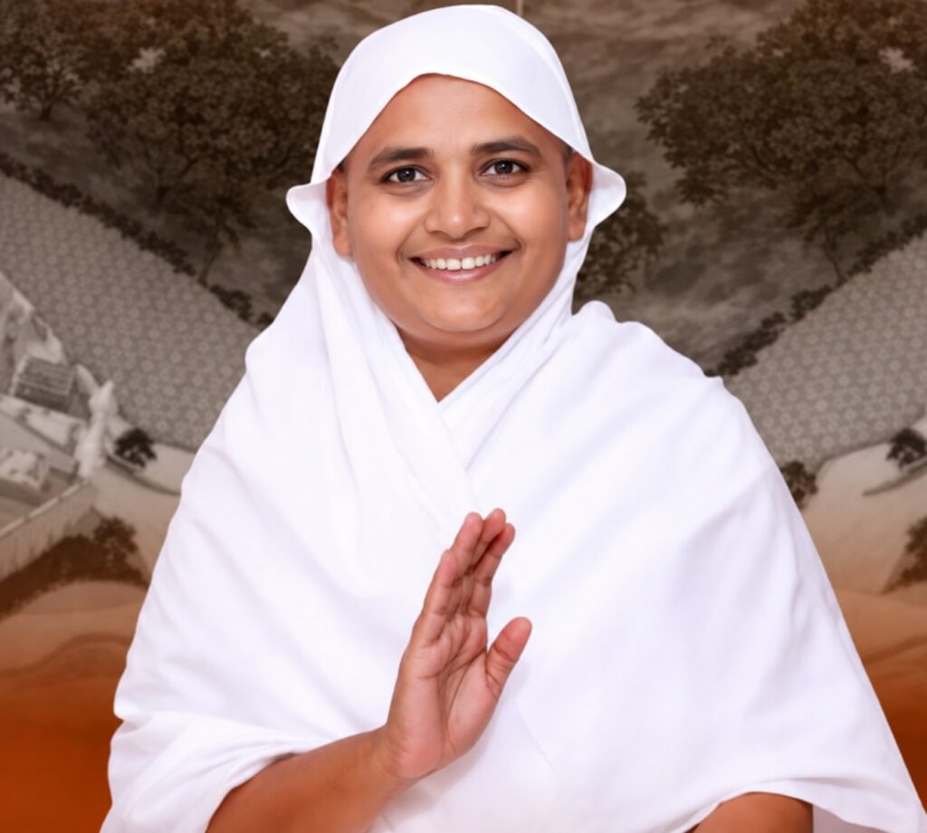 Person in a white robe smiling and holding hands in a prayer-like gesture against a patterned backdrop.