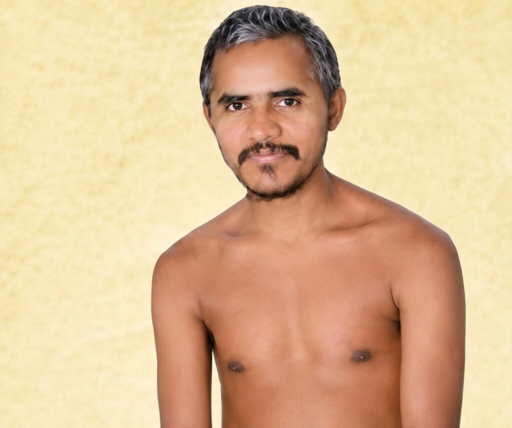 Portrait of a shirtless man with short gray hair and facial hair against a pale yellow textured background