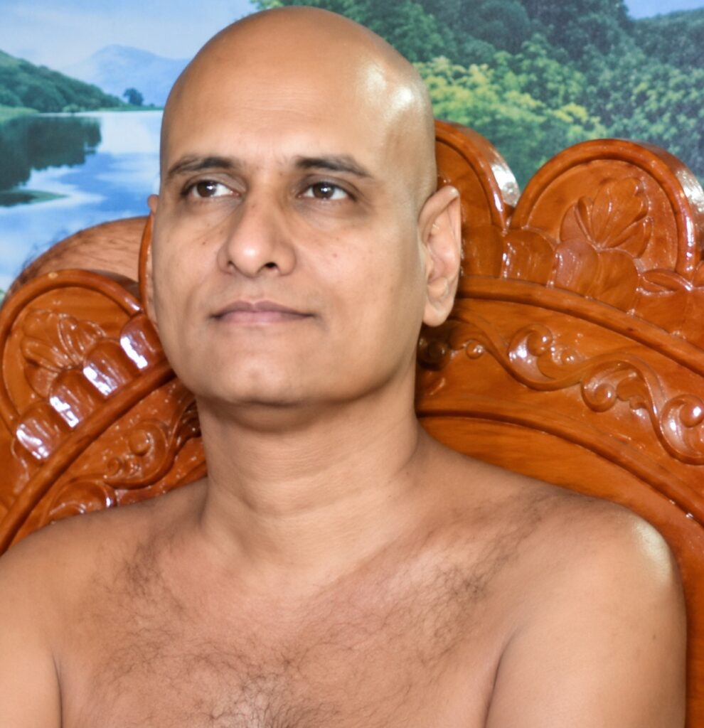 Close-up portrait of a bald man shirtless, sitting on a highly carved wooden chair with a nature backdrop featuring trees and a lake.