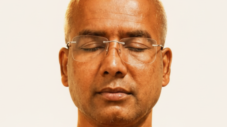 Close-up of a man with short blond hair and glasses, eyes closed, meditating or resting.
