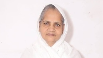Portrait of an elderly woman in a white headscarf, facing the camera with a gentle expression.
