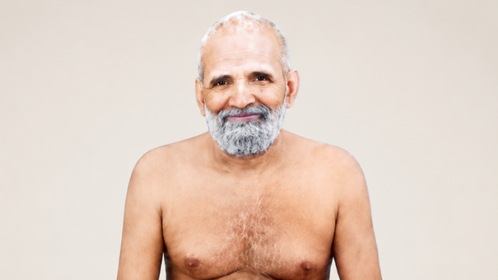 Smiling older man with a gray beard, shirtless against a plain beige background.
