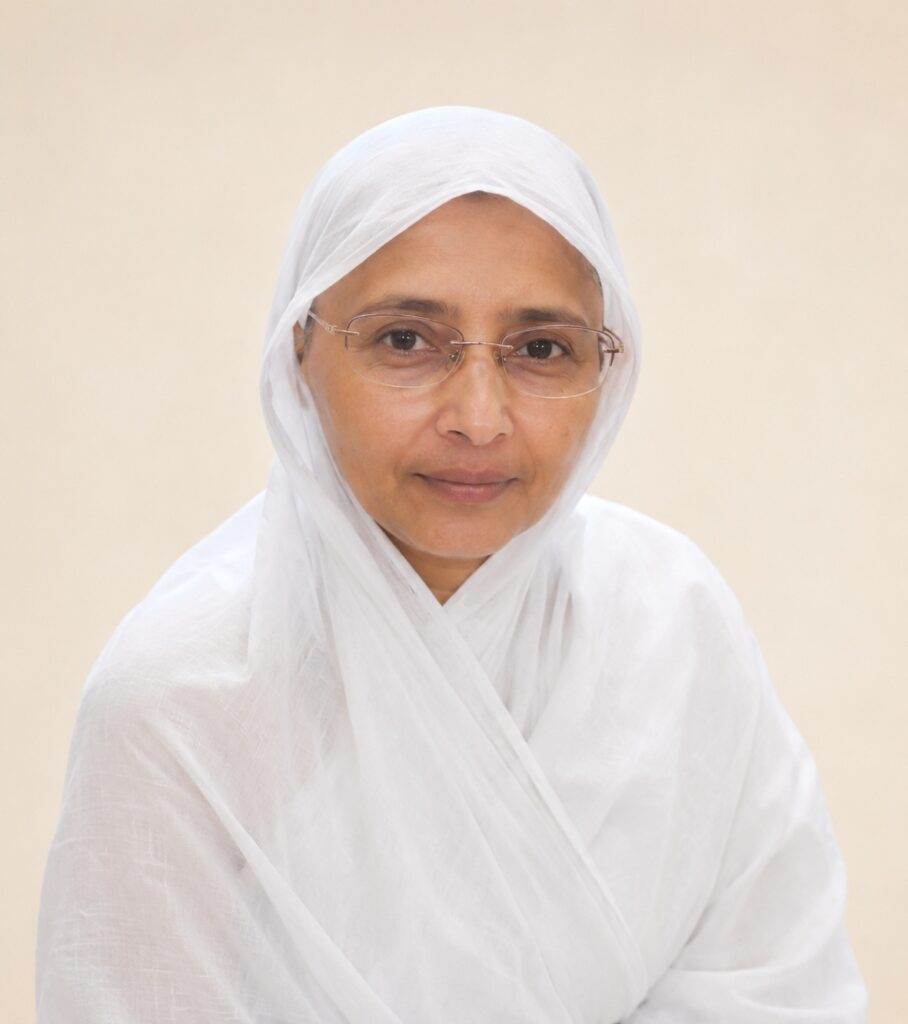 Woman with white headscarf and glasses looking at the camera, neutral expression in a light background.