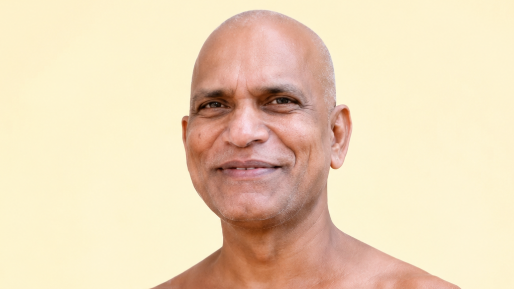 Portrait of a smiling bald man against a pale yellow background, head and shoulders visible, friendly expression.