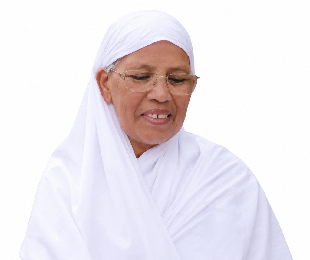 Elderly woman in a white hijab and glasses, looking down with a gentle smile.