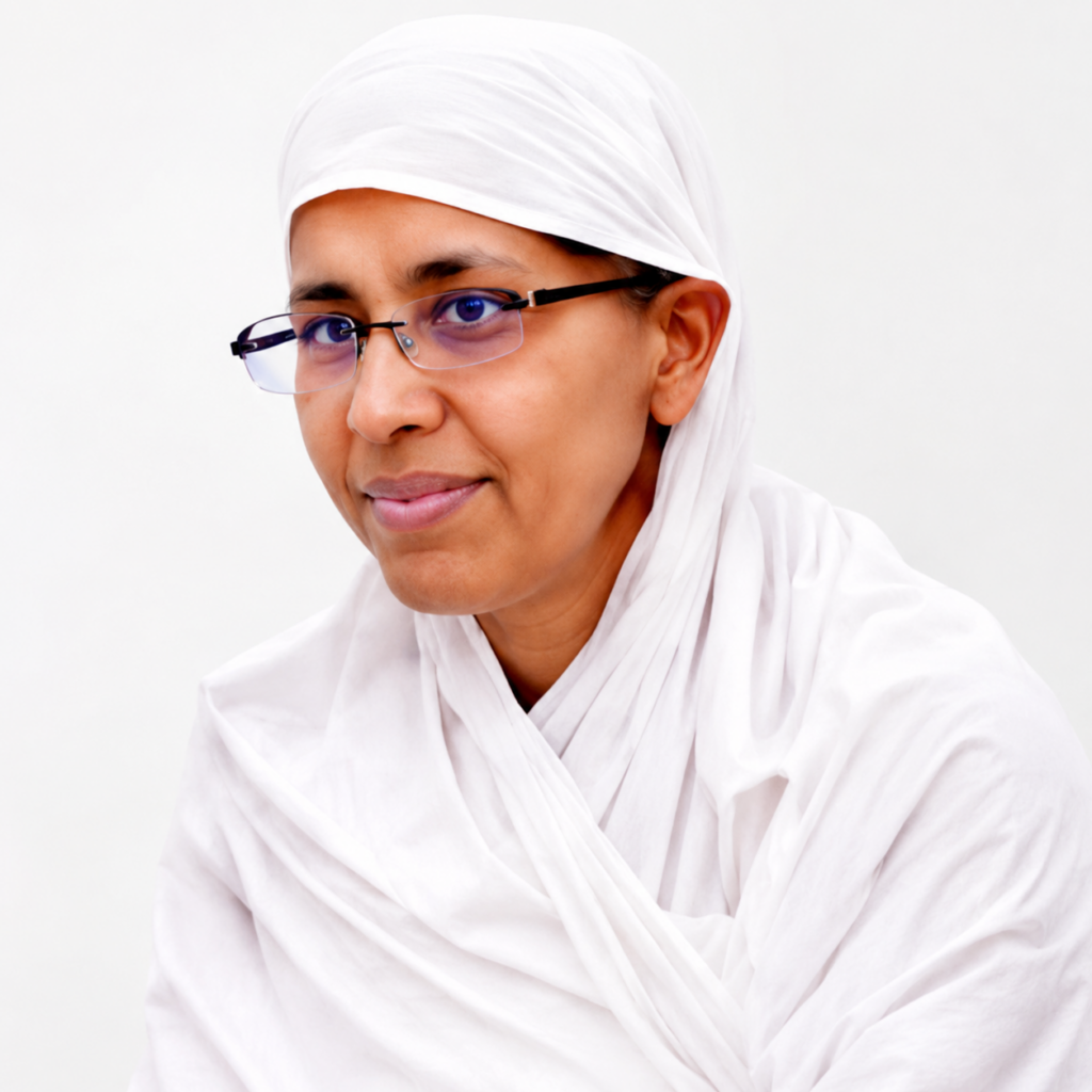 Portrait of a woman wearing a white hijab and glasses, looking at the camera with a gentle smile.
