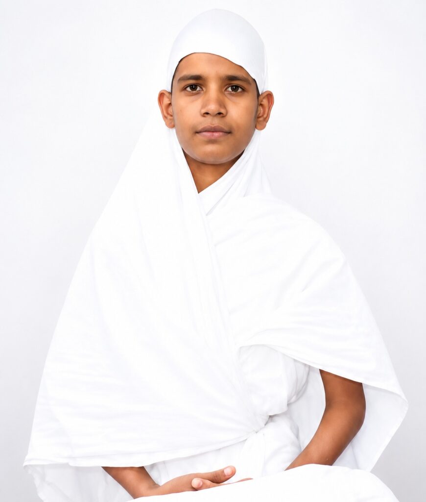 Portrait of a young boy in white traditional clothing, looking at the camera against a white background.