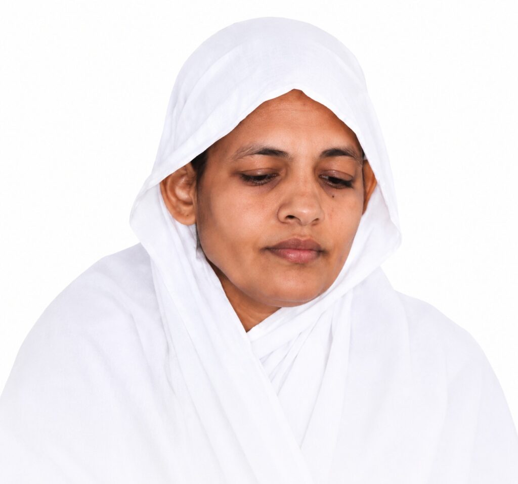 Woman wearing a white hijab looking down with a calm expression.