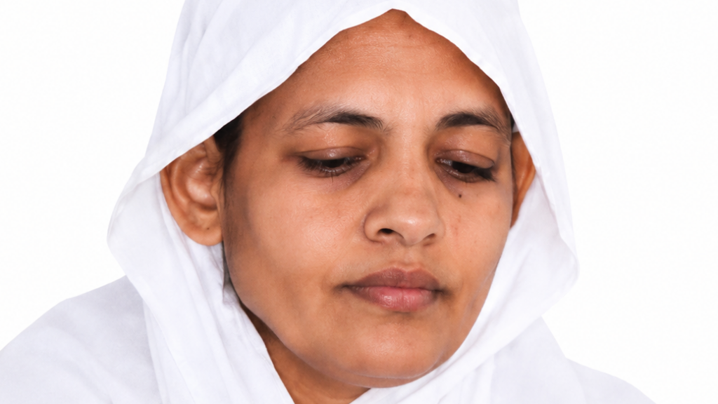 Close-up of a woman wearing a white headscarf, looking downward with a calm expression.