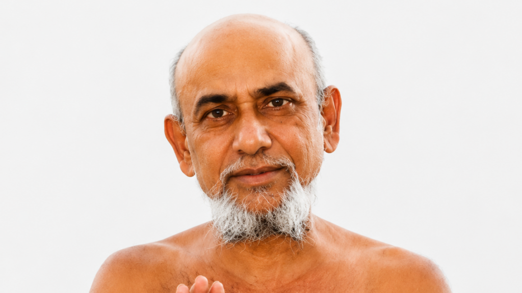 Close-up portrait of an elderly man with a white beard, bare shoulders, and a neutral expression against a light background.
