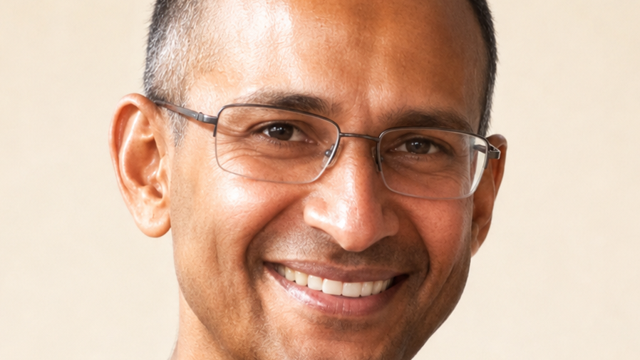 Close-up portrait of a smiling man wearing rectangular glasses facing the camera.