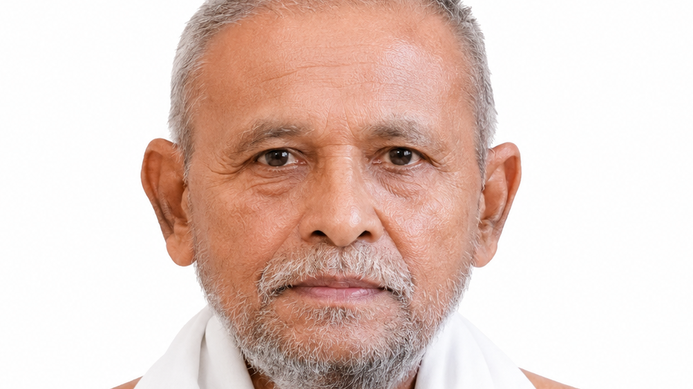Close-up portrait of an older man with short gray hair and beard, wearing a white scarf against a white background.