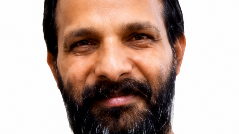 Close-up portrait of a man with a dark beard and mustache, short black hair, and brown eyes, against a white background.