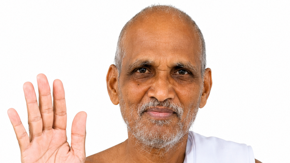Senior man with a white beard waves hello, facing the camera against a white background.