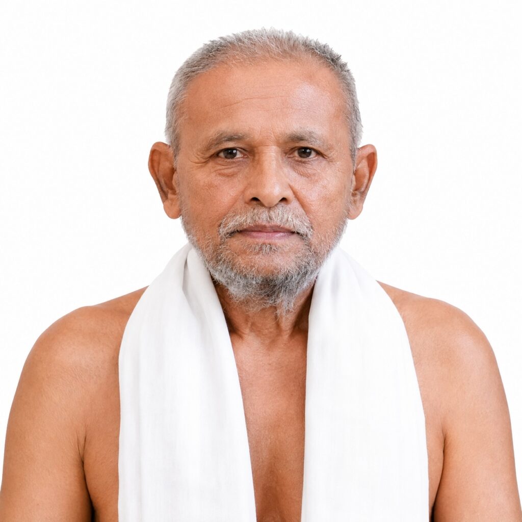 Portrait of an older man with gray hair and beard, wearing a white towel draped over his shoulders against a white background.