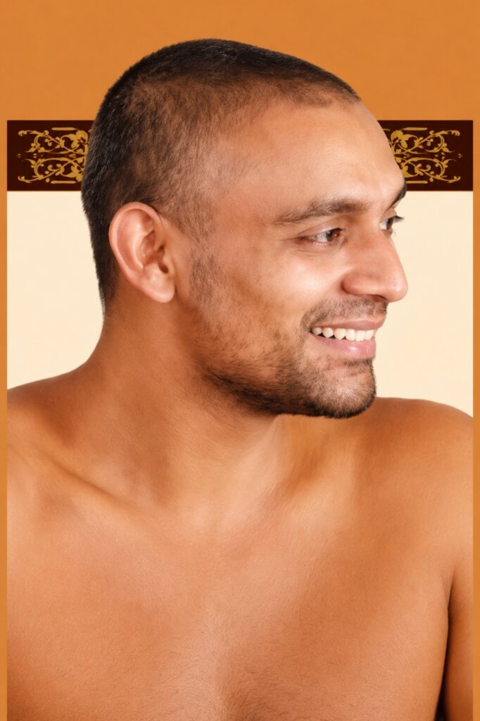 Side-profile portrait of a smiling man with short hair and light stubble, against an orange background at right.