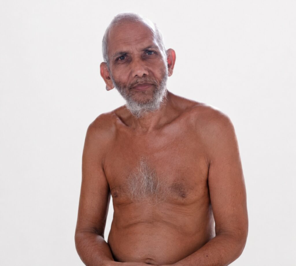 Elderly man with gray beard, shirtless, posing against a plain white background.