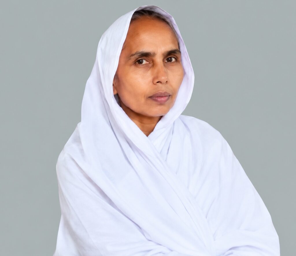 Portrait of a woman in a white headscarf looking to the side against a gray background.