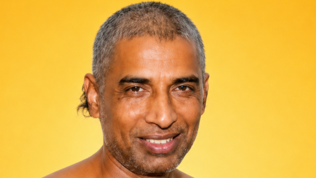 Close-up portrait of a smiling man with short gray hair against a solid yellow background.