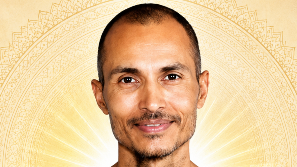 Smiling man with short hair and light stubble against a radiant golden mandala background.