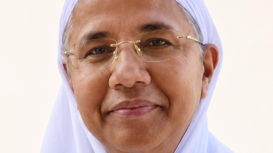 Close-up portrait of a smiling woman wearing a white hijab and gold-rimmed glasses, looking at the camera.