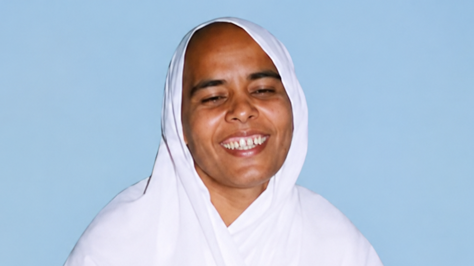 Smiling woman in a white hijab against a light blue background.