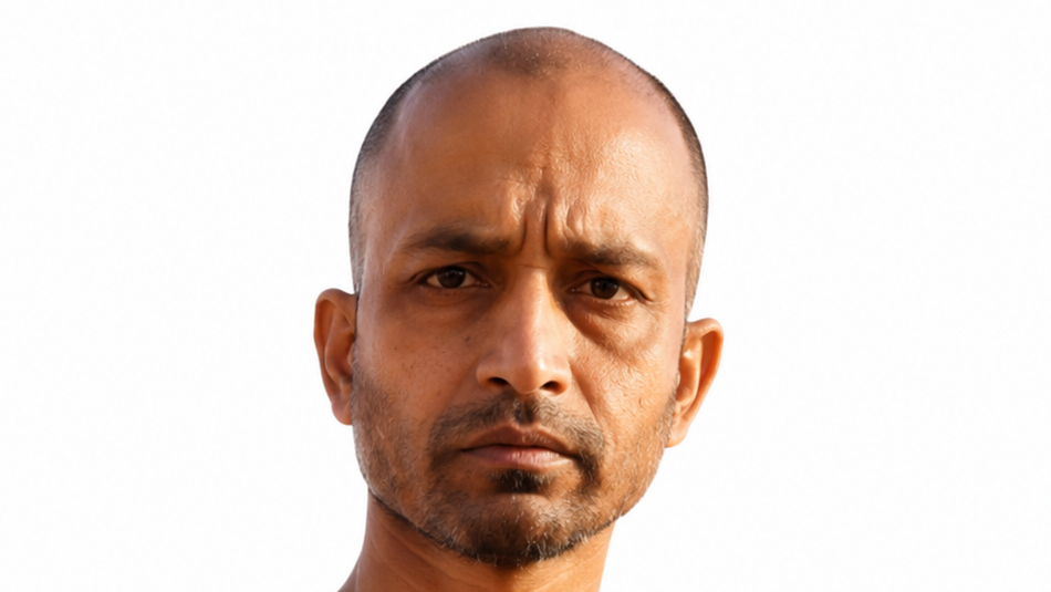 Close-up portrait of a man with a shaved head and stubble, frowning at the camera against a white background.