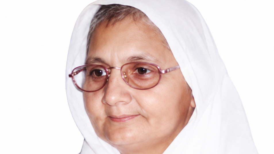 Portrait of a middle-aged woman wearing a white headscarf and pink-rimmed glasses, facing slightly to the left.