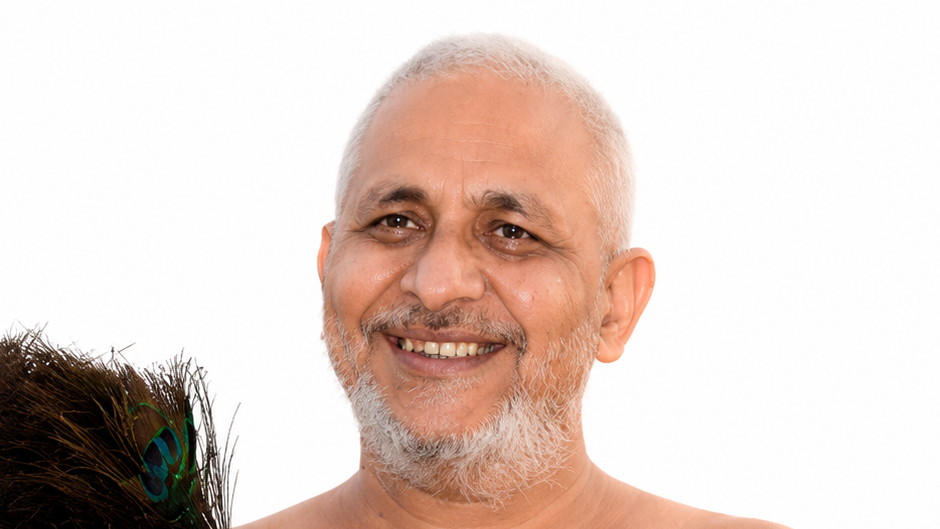 Smiling older man with short white hair and gray beard, bare shoulders, with a peacock feather in the foreground.