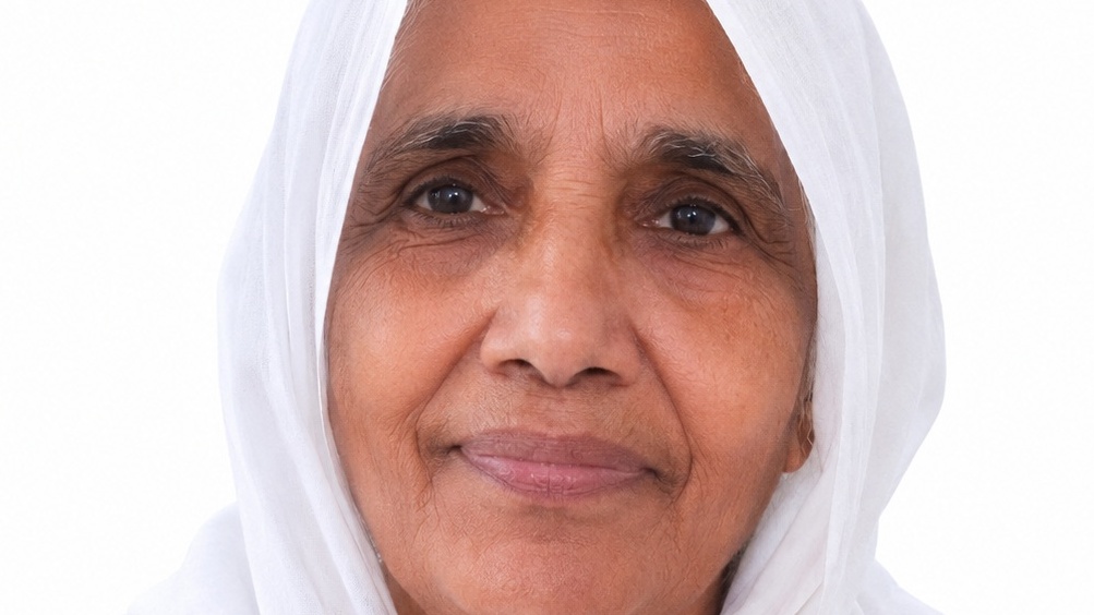 Smiling elderly woman wearing a white headscarf, close-up portrait against a plain background