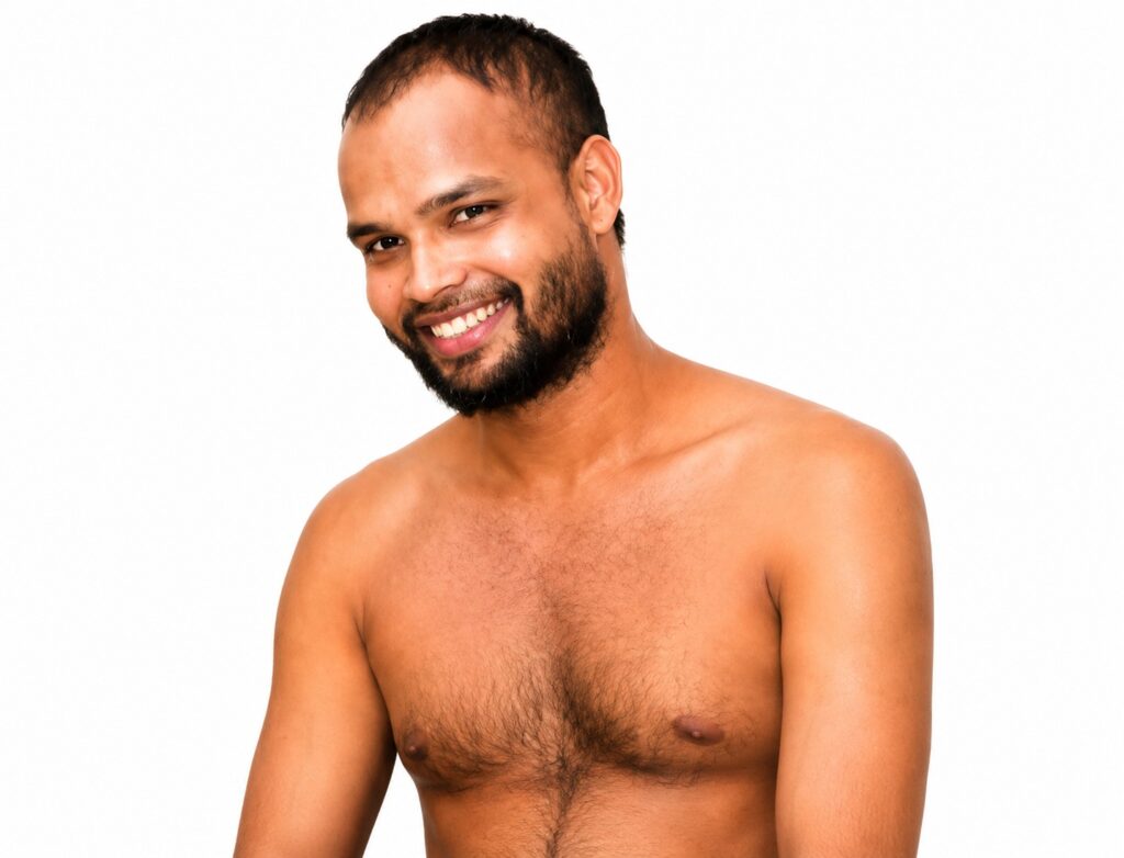 Smiling man with a beard and short hair, shirtless, against a white studio backdrop.