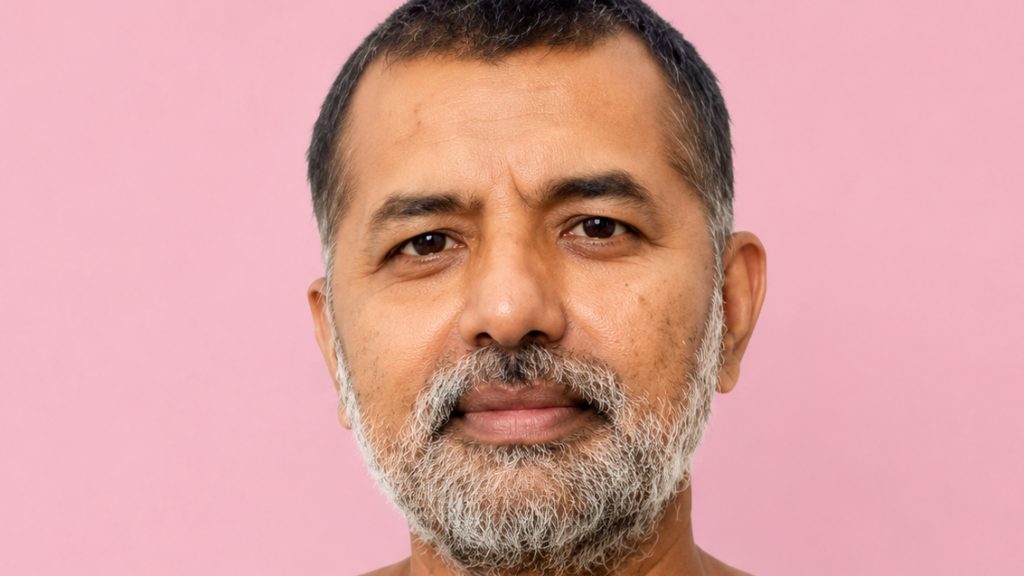 Close-up portrait of a middle-aged man with a gray beard against a pink background.